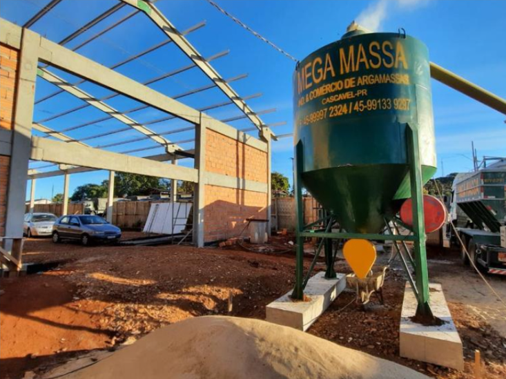 Caminhão Mega Massa estacionado em frente à obra